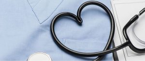 photo of stethoscope in the shape of a heart on top of blue scrubs